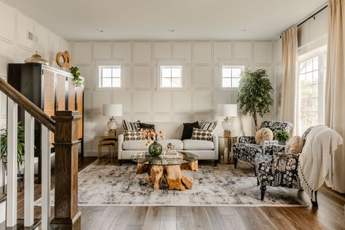 Living room with a black cane cabinet, neutral sofa and a staircase in the foreground