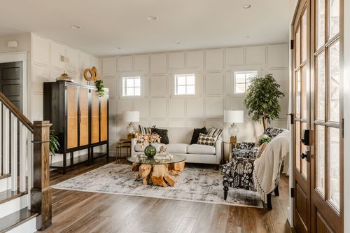 Two-story living room with a black paneled fireplace wall and brass chandeliers