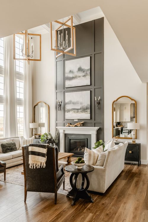 Living room with a black fireplace wall, gold mirrors and floor-to-ceiling windows