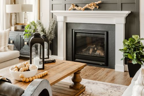 Living room fireplace with a white mantle, wood coffee table and lantern decor