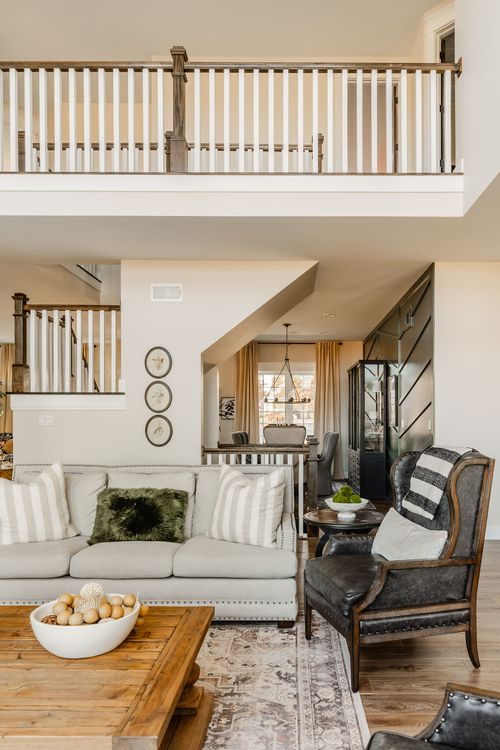 Two-story great room with a wood-railed loft overlook, cream sofa and dark leather armchairs