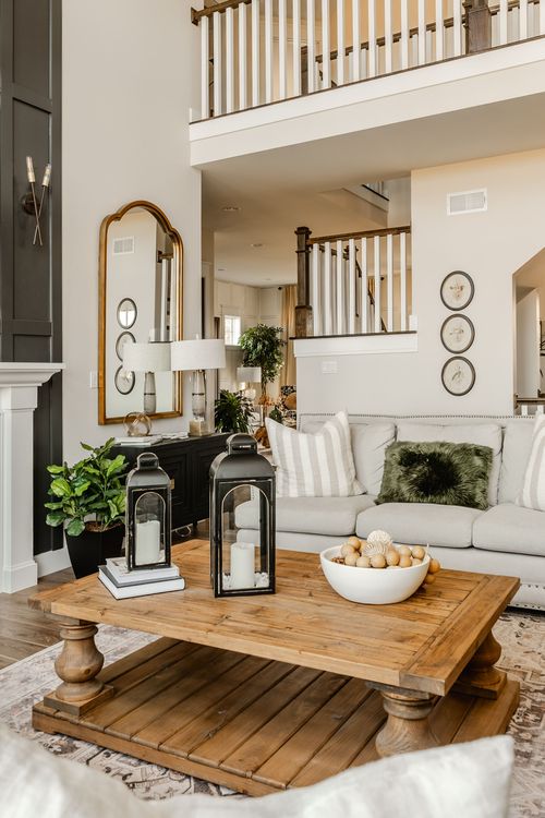 Great room corner with gold arched mirror, black lanterns and wood coffee table below a loft railing