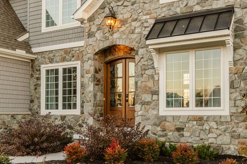 Close view of a stone entrance with an arched wood door and hanging lantern