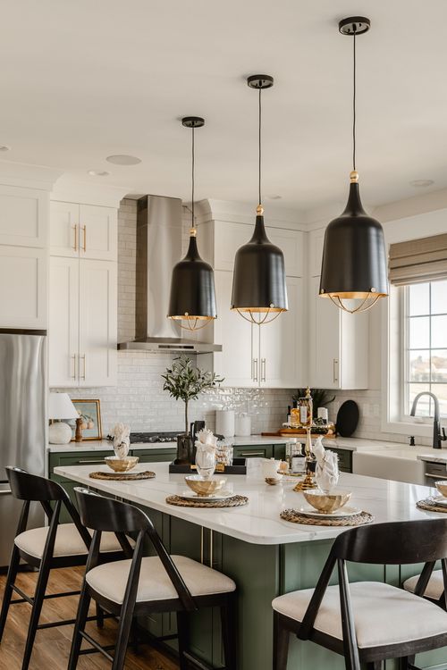 Kitchen with black dome pendants over a sage island and tile backsplash