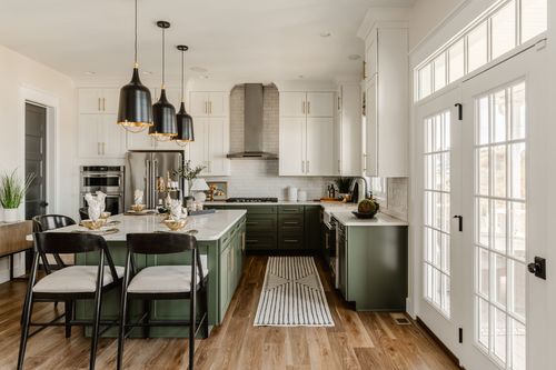 Kitchen with sage island, black chairs and glass French doors leading outside