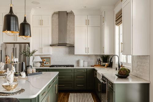 Kitchen with stainless range hood, tile backsplash and sage lower cabinets