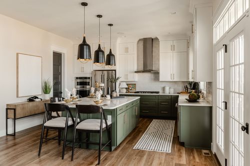 Kitchen island set for a meal beneath black dome pendant lights