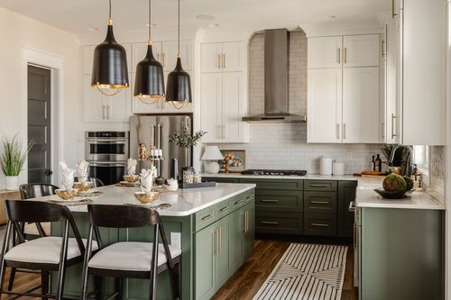 Kitchen with black pendant lights, sage cabinetry and a striped runner rug