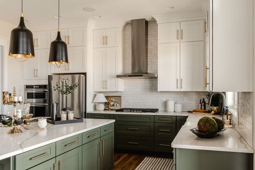 Kitchen with sage cabinetry, stainless appliances and black pendant lighting