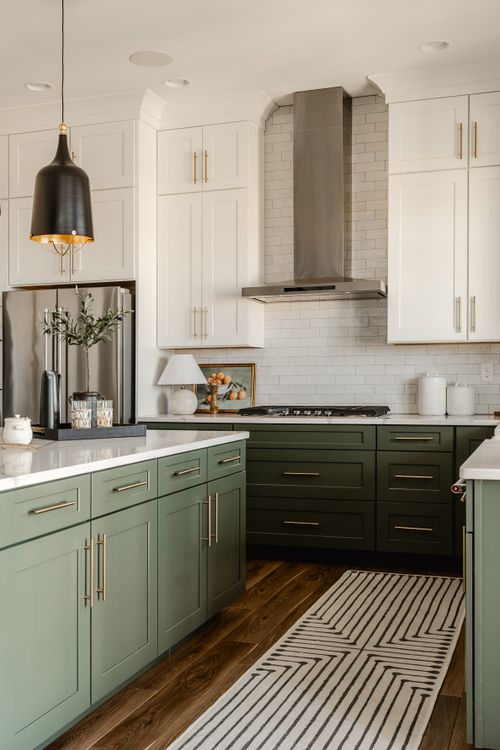 Kitchen corner with stainless range hood, tile backsplash and sage cabinets