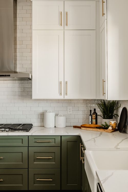 Kitchen counter detail with white cabinets, brass hardware and marble countertop