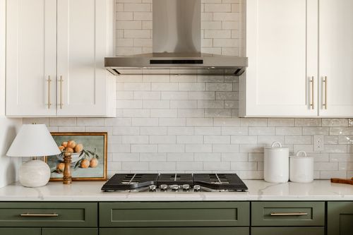 Kitchen cooktop area with tile backsplash and marble countertops