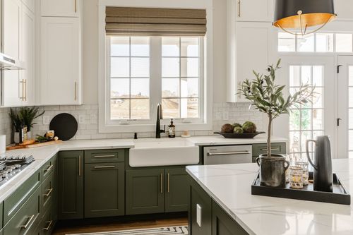Kitchen counter with cooktop, tile backsplash and sage green cabinets