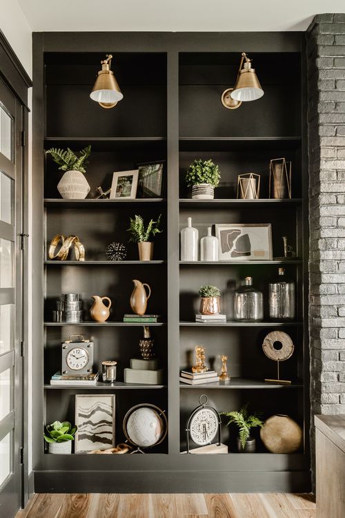 Built-in shelving with brass sconces styled with books, plants and decor