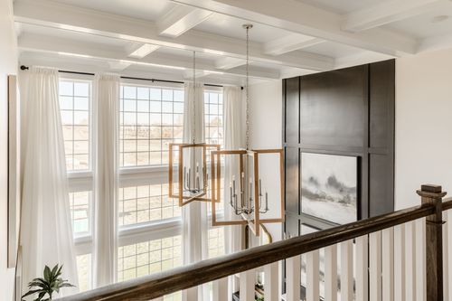 Upstairs landing with coffered ceiling, gold candelabra chandeliers and tall windows