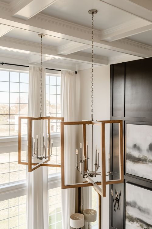 Close-up of gold-framed candelabra chandeliers hanging under a coffered ceiling