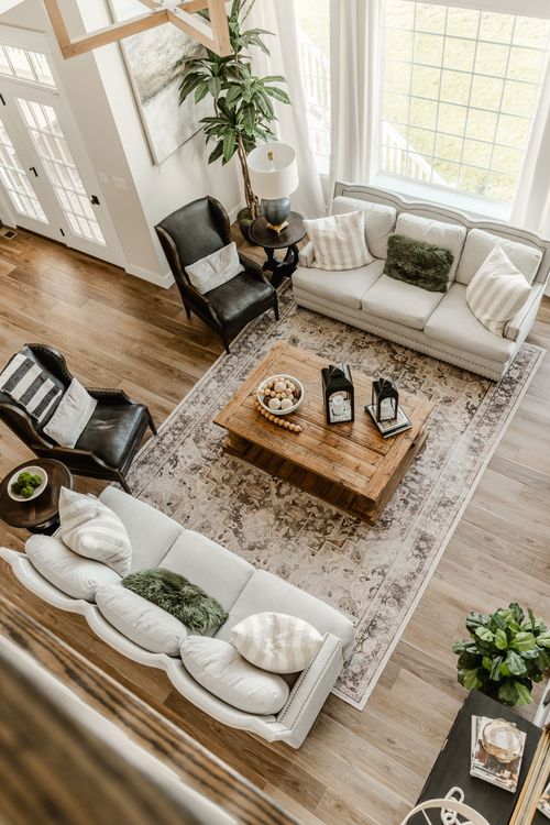 Aerial view of a great room with sectional sofa, leather chairs and a patterned area rug