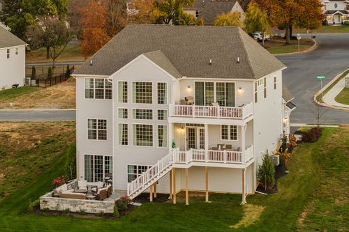 Aerial rear view of a three-story home with multiple decks and a stone patio