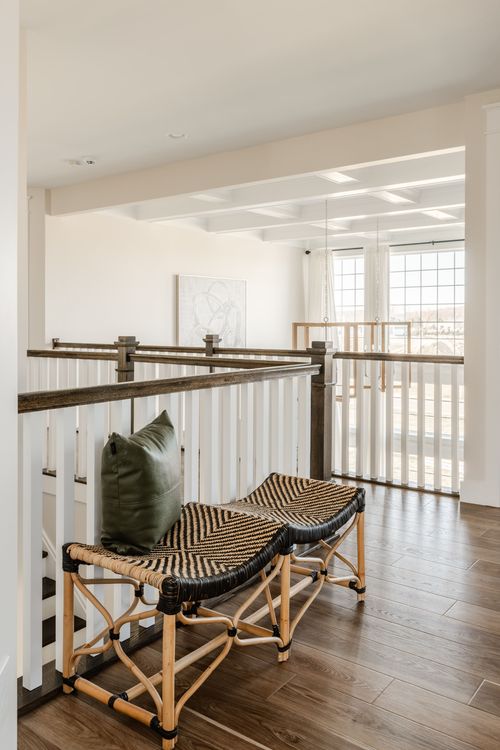 Upstairs landing with woven bench seating, dark wood railing and framed art