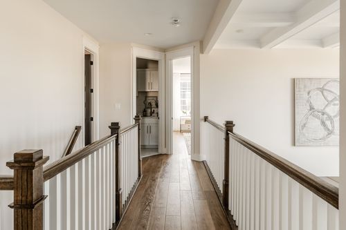 Upstairs hallway with wood flooring leading past a coffered ceiling to a bedroom