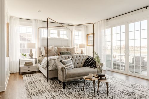 Primary bedroom with gold canopy bed, tufted bench and sheer curtains