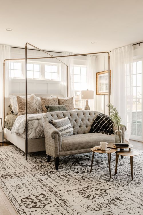 Primary bedroom with canopy bed, tufted loveseat and patterned area rug