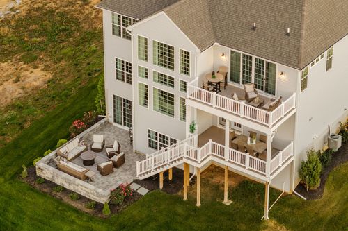 Aerial view of a layered stone patio with outdoor seating below a multi-level deck