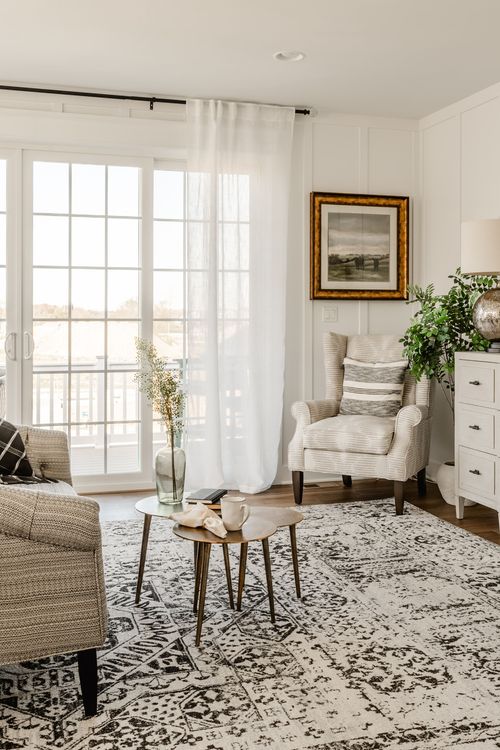 Bedroom seating nook with cream armchair, framed art and potted plant near French doors