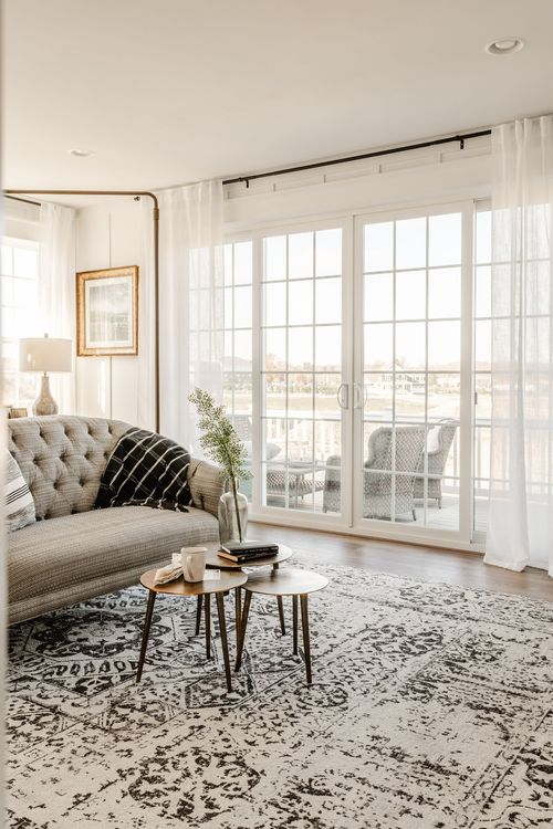 Sitting room with tufted sofa, layered rug and a private balcony view