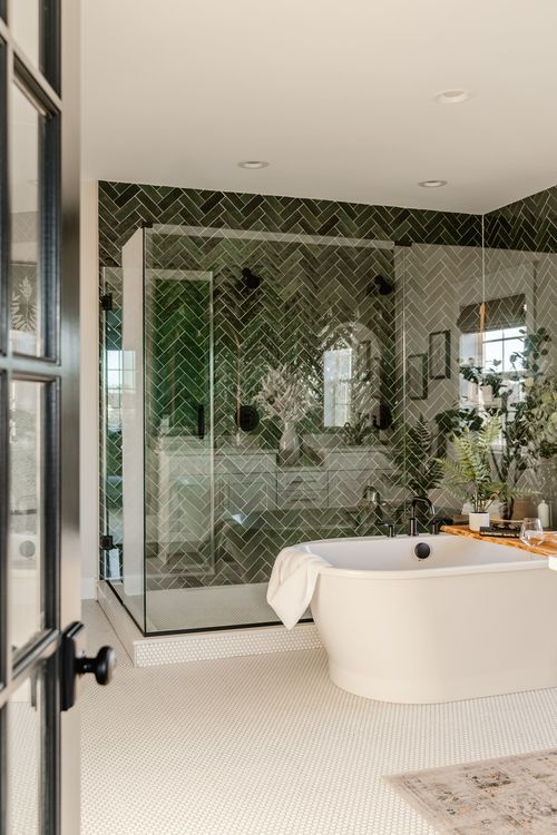 Bathroom with green herringbone tile, glass shower and freestanding soaking tub