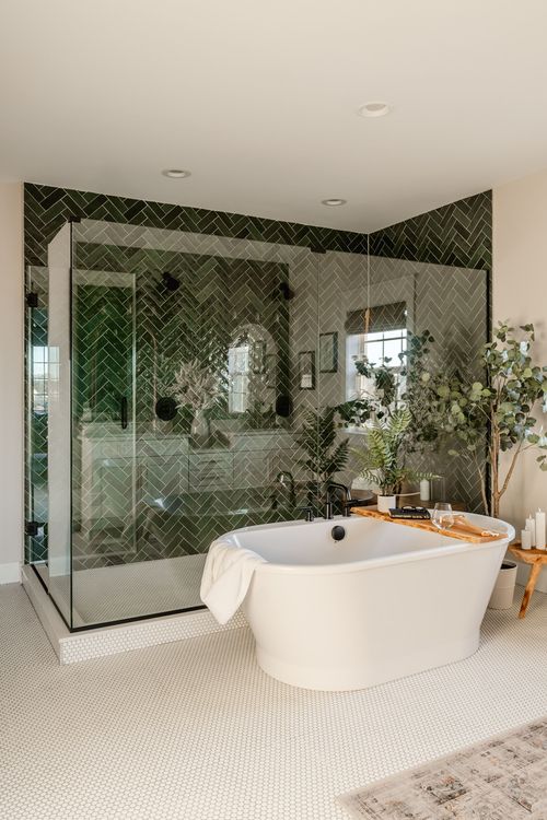 Bathroom with green herringbone tile wall, freestanding tub and potted plants