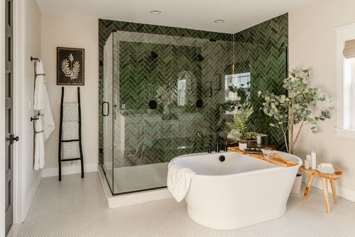Bathroom with green herringbone tile shower, ladder towel rack and freestanding tub
