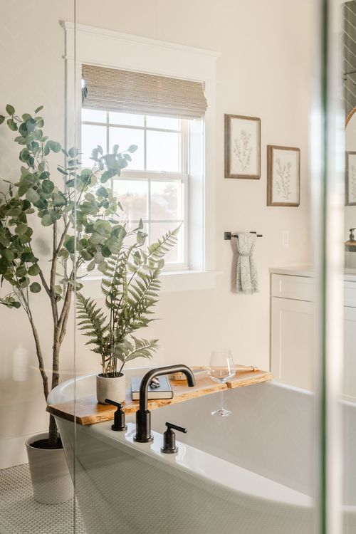 Bathroom with freestanding tub, potted plants and a wood-slat window shade