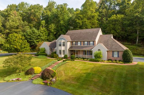 Aerial view of a brick and stucco home with a curved brick walkway and landscaped beds