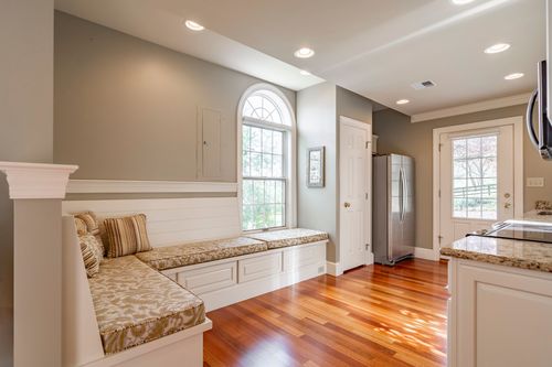 Built-in banquette seating below an arched window beside a stainless refrigerator