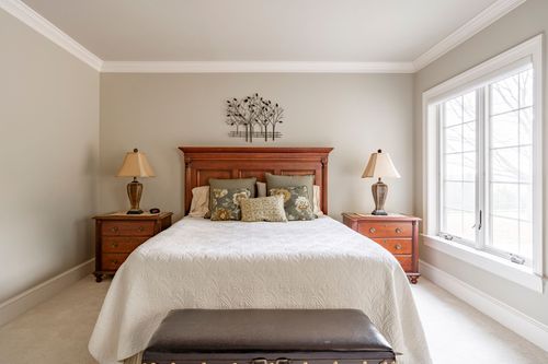 Bedroom with a cherry sleigh bed, crisp white bedding, and a large window