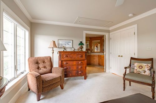 Sitting nook outside the primary bath with a leopard-print recliner and antique dresser