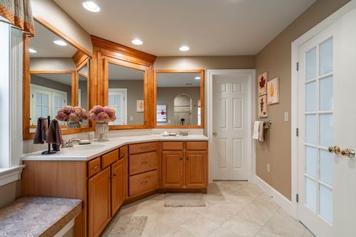 Primary bathroom with dual wood-framed mirrors and granite countertops