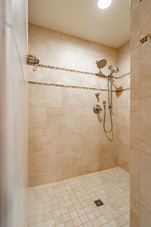 Neutral tiled walk-in shower with a rain showerhead and mosaic accent strips