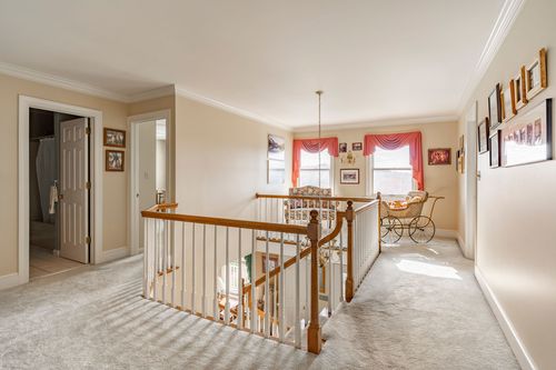 Upstairs landing with a white stair railing and carpeted hallway