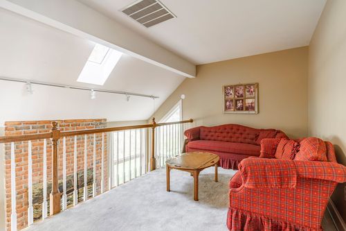Bonus loft with a skylight, brick half-wall railing, and red plaid sofa seating