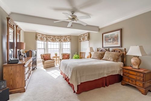 Primary bedroom with a bay-window sitting area, tray ceiling, and matching dressers