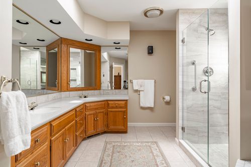 Bathroom with a corner vanity, glass-enclosed shower, and tile flooring