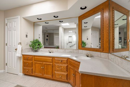 Corner double vanity with oak cabinetry and mirrored medicine cabinets