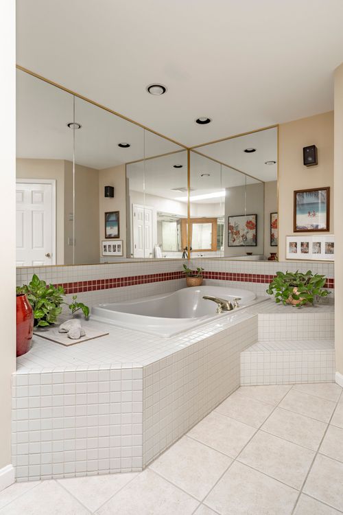 Jetted corner soaking tub with a tile surround and mirrored walls