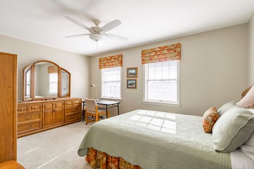 Bedroom with a matching oak dresser and desk beneath patterned window valances