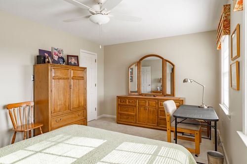 Bedroom with a wood armoire, oak dresser, and a small desk tucked under the window