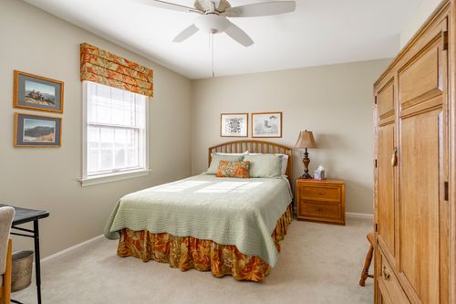 Bedroom with a wood spindle headboard, floral bedskirt, and a tall oak armoire