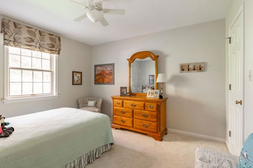 Bedroom with a mirrored oak dresser, ceiling fan, and neutral bedding