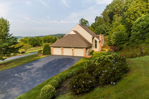 Aerial view of a home's three-car garage and paved driveway framed by hydrangeas